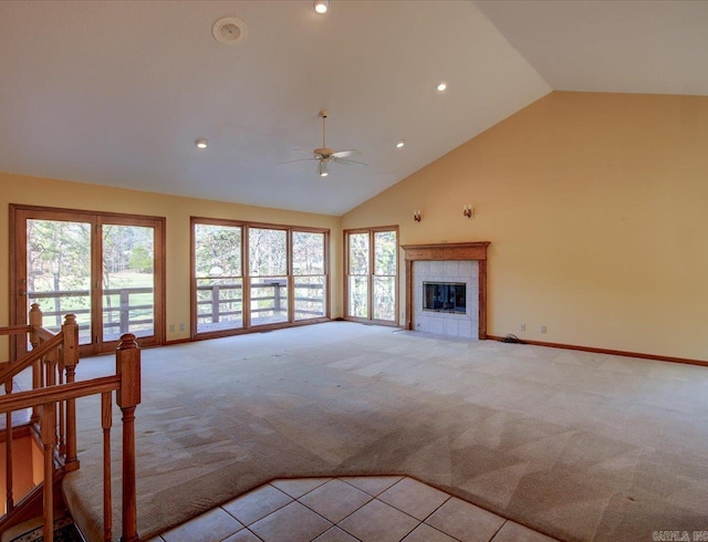 unfurnished living room with high vaulted ceiling, a tiled fireplace, light carpet, and ceiling fan