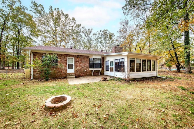 back of house featuring a lawn, a sunroom, a fire pit, and a patio area