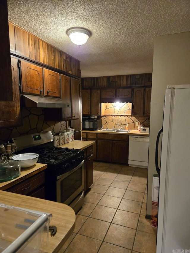 kitchen featuring tasteful backsplash, a textured ceiling, light tile patterned floors, sink, and white appliances