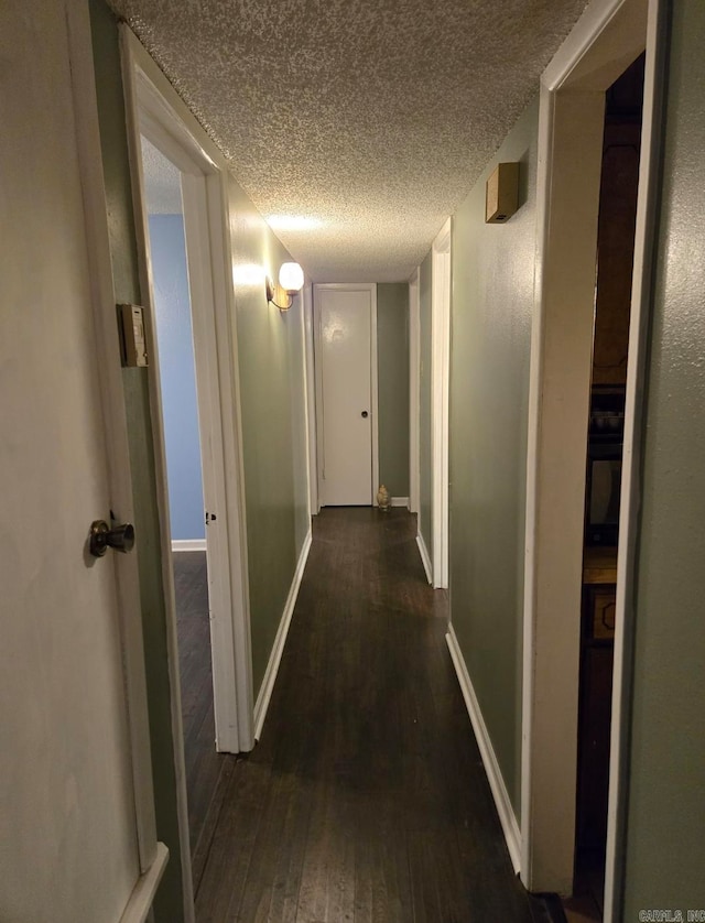 hallway with dark hardwood / wood-style floors and a textured ceiling