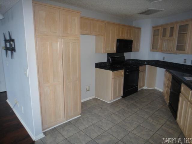 85 Bluff View Dr, Quitman, AR 72131 - kitchen featuring black appliances, dark countertops, light brown cabinetry, glass insert cabinets, and baseboards