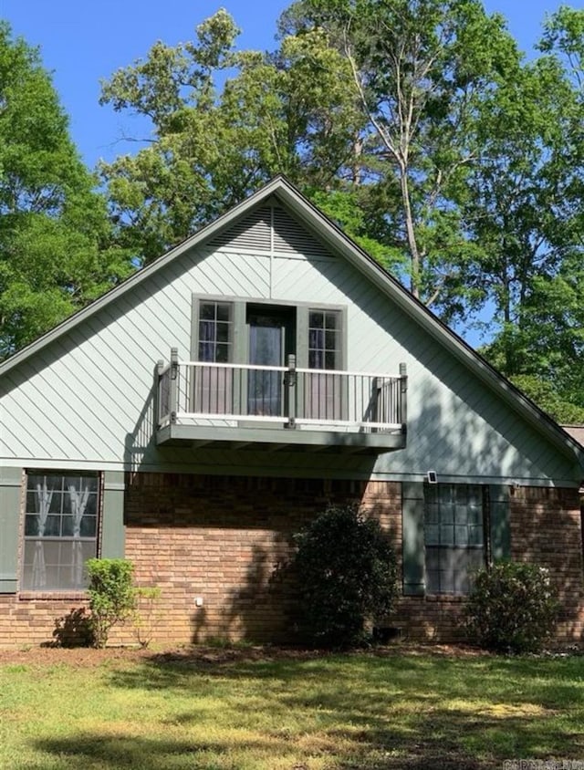 rear view of property featuring a lawn and a balcony