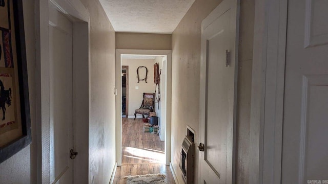 hallway with hardwood / wood-style floors and a textured ceiling