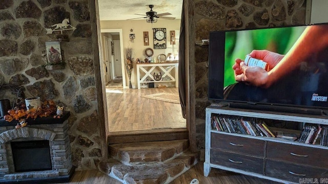 interior details featuring hardwood / wood-style floors, a fireplace, a textured ceiling, and ceiling fan