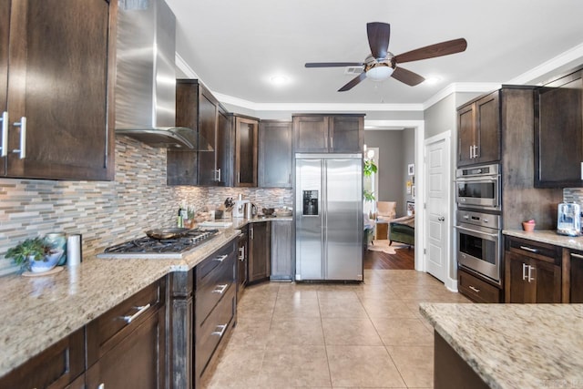 kitchen with crown molding, stainless steel appliances, wall chimney exhaust hood, and light stone counters