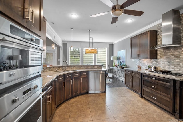 kitchen with sink, appliances with stainless steel finishes, ornamental molding, light stone countertops, and wall chimney exhaust hood