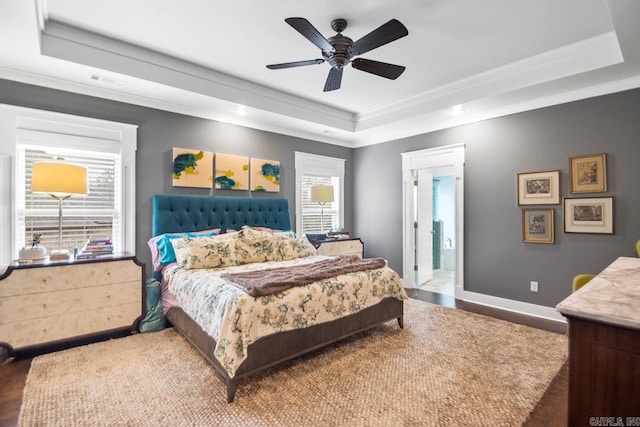 bedroom featuring hardwood / wood-style flooring, ceiling fan, multiple windows, and a tray ceiling