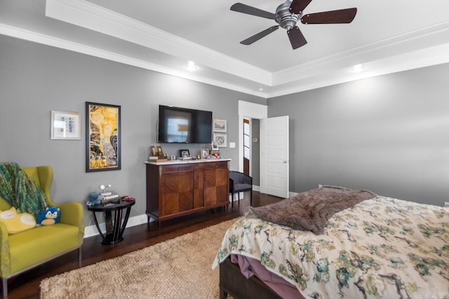 bedroom featuring dark hardwood / wood-style flooring, ceiling fan, crown molding, and a tray ceiling