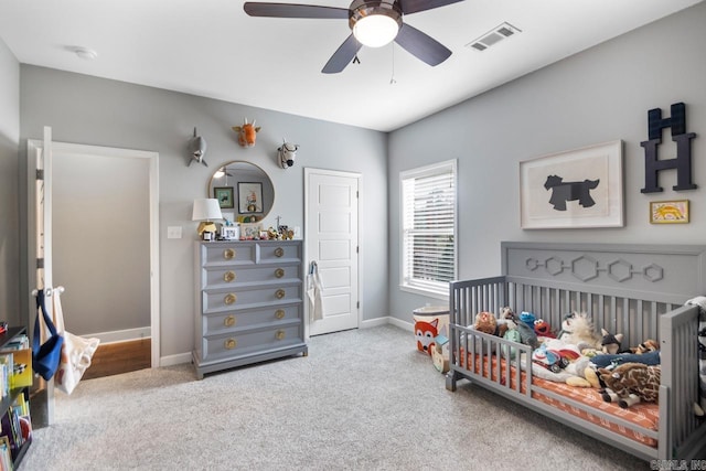 carpeted bedroom featuring a fireplace, a crib, and ceiling fan