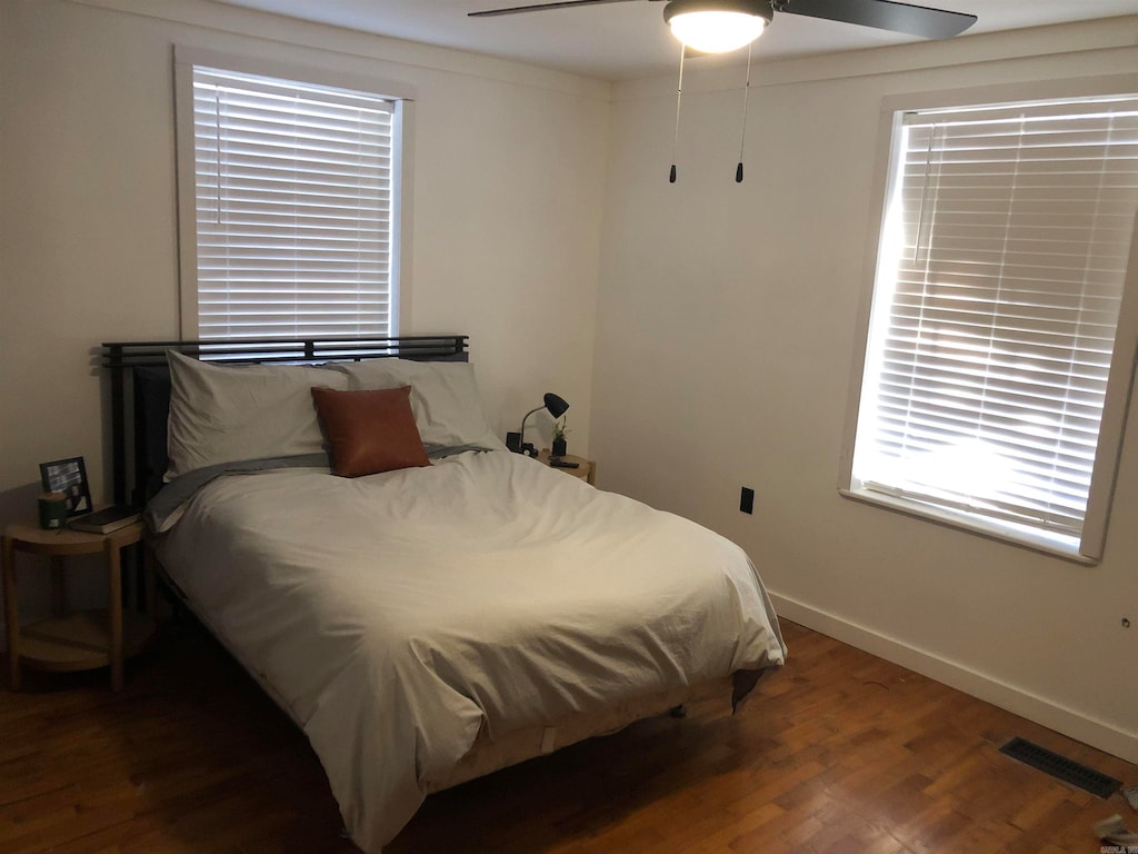 bedroom featuring ceiling fan, multiple windows, and dark hardwood / wood-style flooring