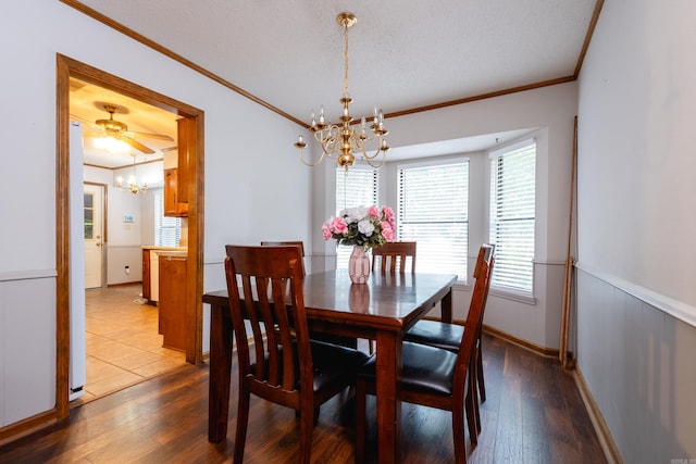 dining space featuring wood-type flooring, a textured ceiling, ceiling fan with notable chandelier, and ornamental molding