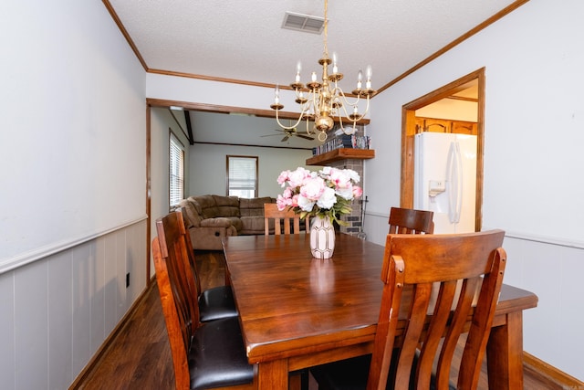 dining space with ceiling fan with notable chandelier, a textured ceiling, wooden walls, ornamental molding, and dark hardwood / wood-style floors