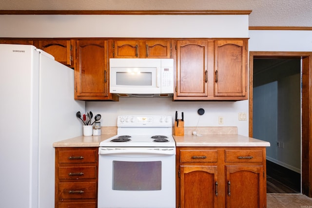 kitchen featuring white appliances, a textured ceiling, light tile patterned floors, and crown molding