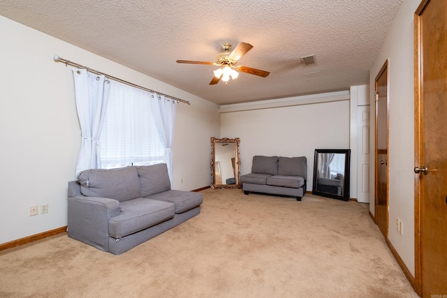 living room featuring ceiling fan, light colored carpet, and a textured ceiling