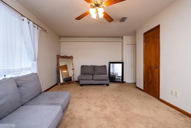 carpeted living room featuring a textured ceiling and ceiling fan