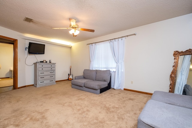 sitting room with ceiling fan, light colored carpet, and a textured ceiling