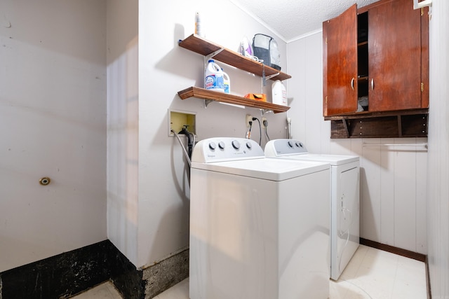 clothes washing area with washer and clothes dryer, wooden walls, cabinets, and a textured ceiling