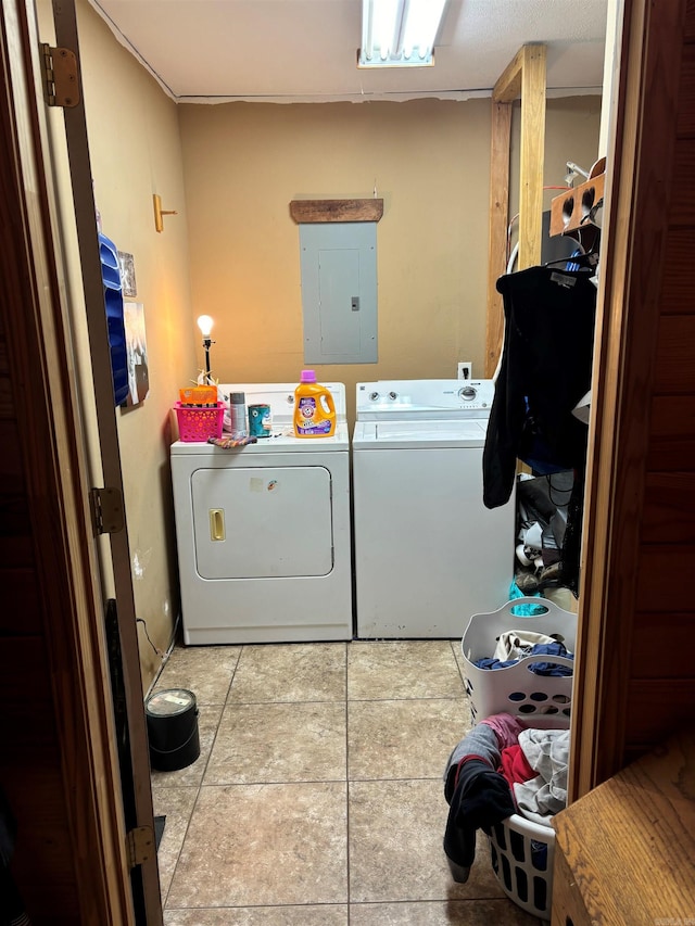 laundry area with electric panel, light tile patterned floors, and washing machine and clothes dryer