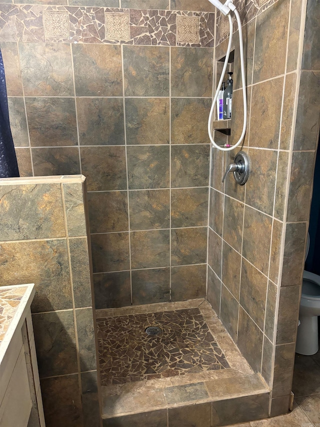 bathroom with vanity, toilet, and a tile shower