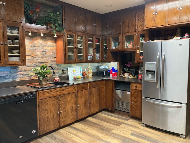 kitchen with light hardwood / wood-style floors, sink, stainless steel fridge, decorative backsplash, and black dishwasher