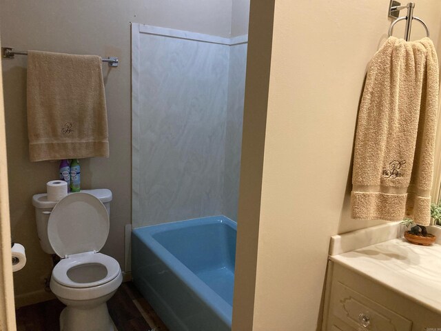 bathroom featuring a bath, hardwood / wood-style flooring, toilet, and vanity