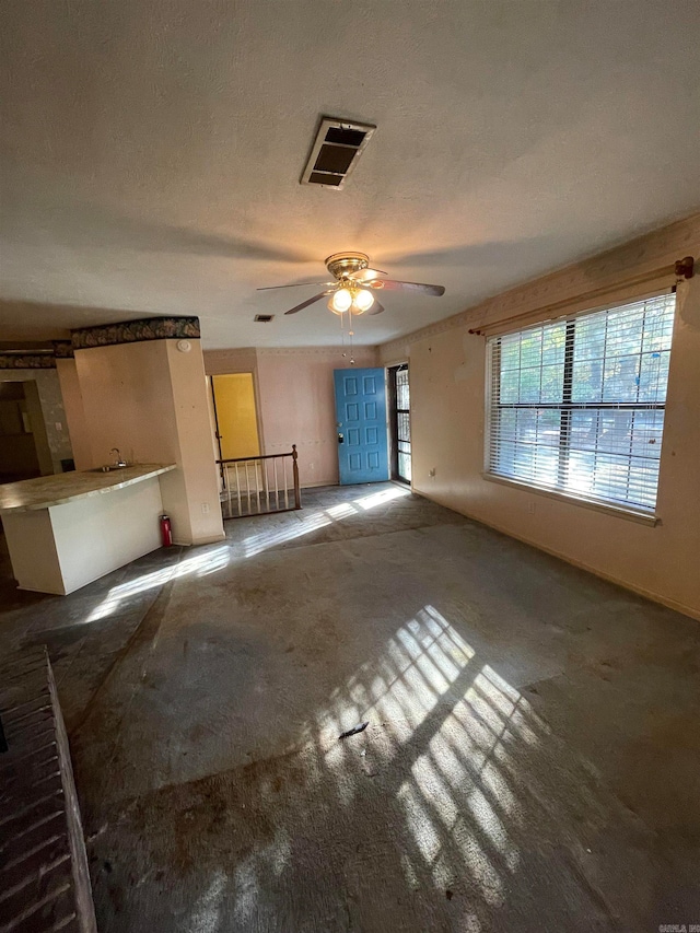 unfurnished living room with a textured ceiling and ceiling fan