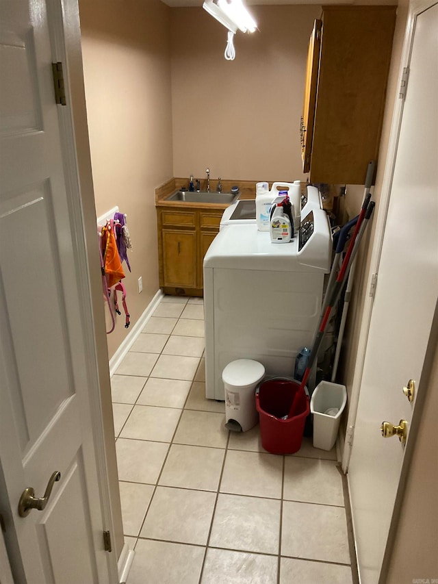 washroom with cabinets, light tile patterned floors, sink, and washing machine and clothes dryer