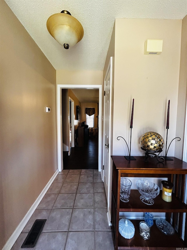 hall with a textured ceiling and tile patterned floors