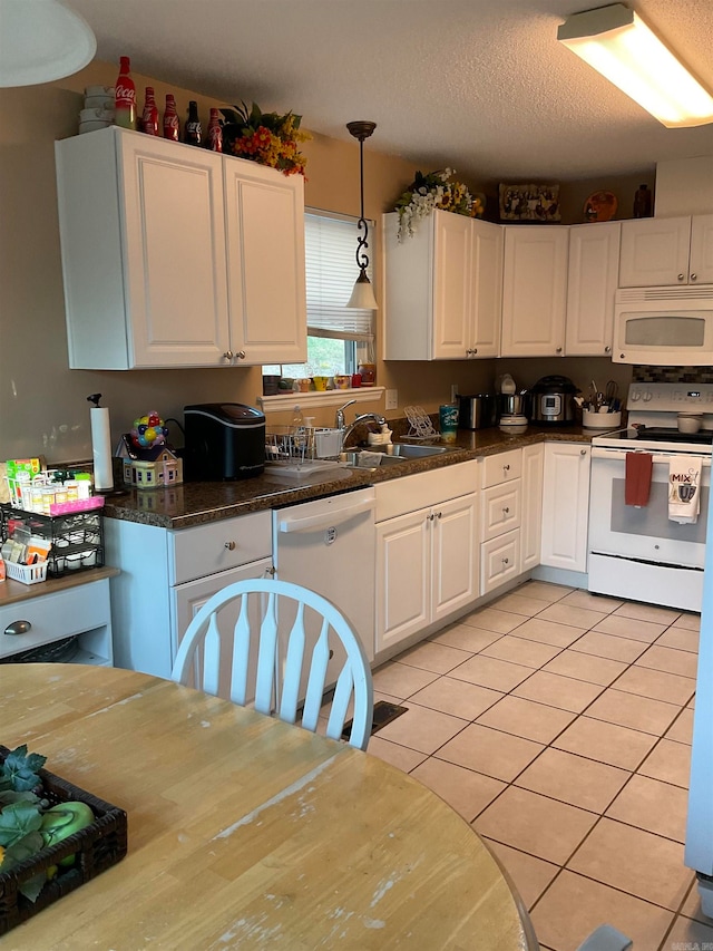 kitchen with white appliances, white cabinets, sink, hanging light fixtures, and light tile patterned flooring