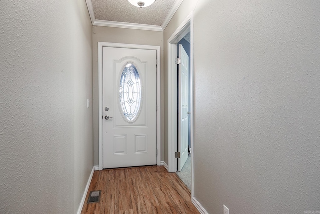 doorway to outside with a textured ceiling, light wood-type flooring, and crown molding