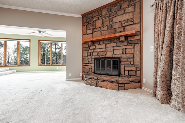 unfurnished living room featuring a stone fireplace, ceiling fan, ornamental molding, a textured ceiling, and carpet floors