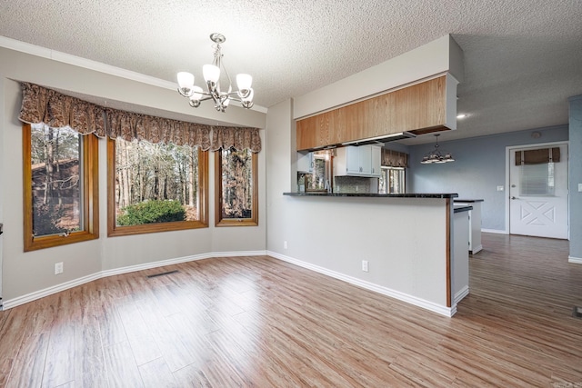 kitchen featuring kitchen peninsula, pendant lighting, a textured ceiling, and a chandelier