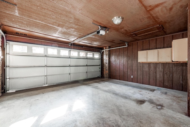 garage featuring a garage door opener and wood walls