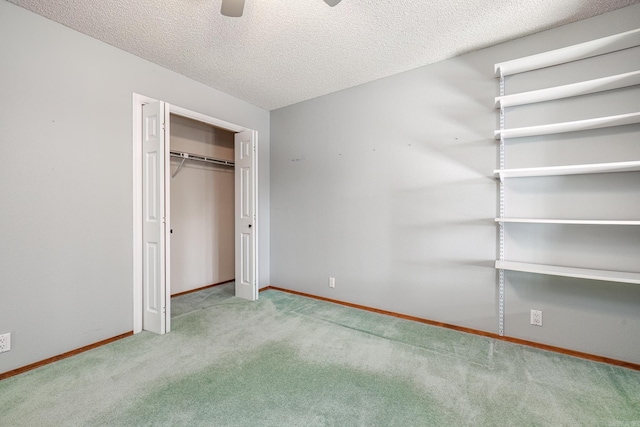 unfurnished bedroom featuring a closet, a textured ceiling, carpet floors, and ceiling fan