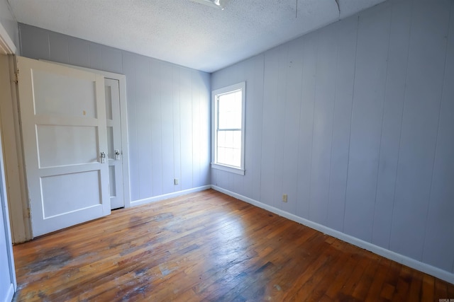 spare room featuring a textured ceiling, wood walls, and hardwood / wood-style flooring