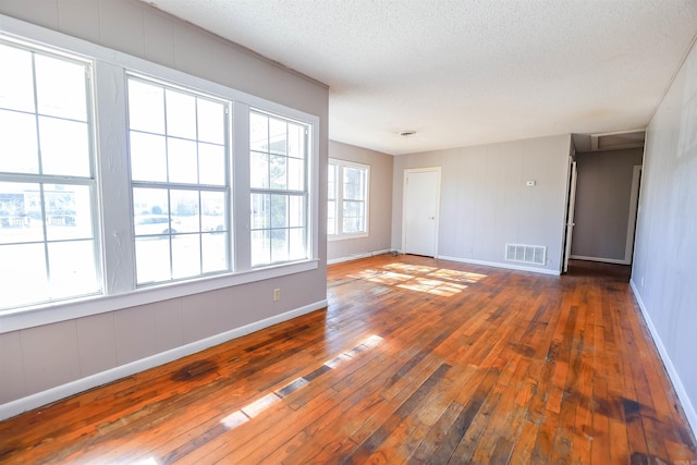 unfurnished room featuring a wealth of natural light, dark hardwood / wood-style floors, and a textured ceiling