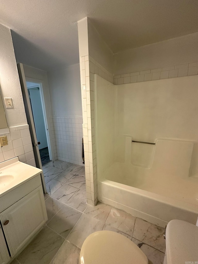 full bathroom with toilet, vanity, tile walls, and shower / bathtub combination