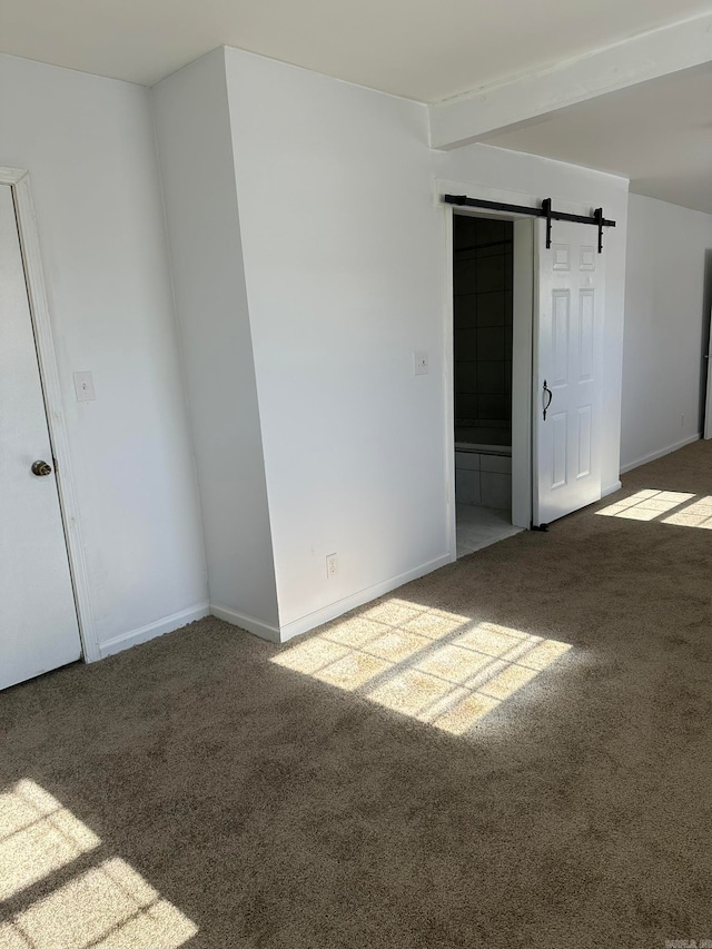 carpeted empty room with a barn door