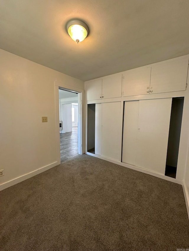 unfurnished bedroom featuring a closet and dark carpet