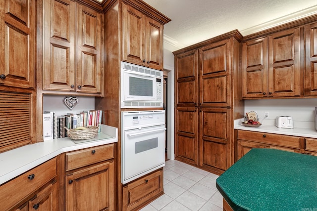 kitchen with white appliances, a textured ceiling, and light tile patterned flooring