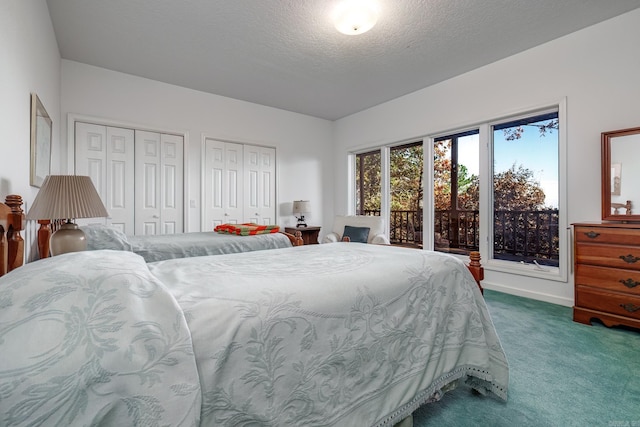 bedroom with two closets, a textured ceiling, and carpet floors