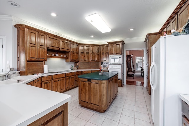 kitchen featuring light tile patterned flooring, crown molding, sink, white appliances, and a center island