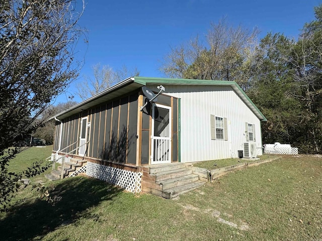 back of property featuring a lawn and entry steps