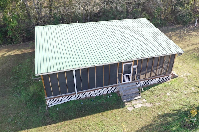 exterior space featuring a lawn, a sunroom, and metal roof