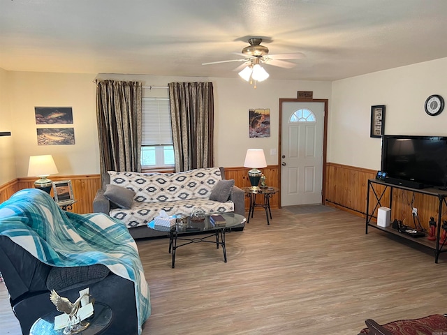 living room featuring light hardwood / wood-style floors, ceiling fan, and wooden walls