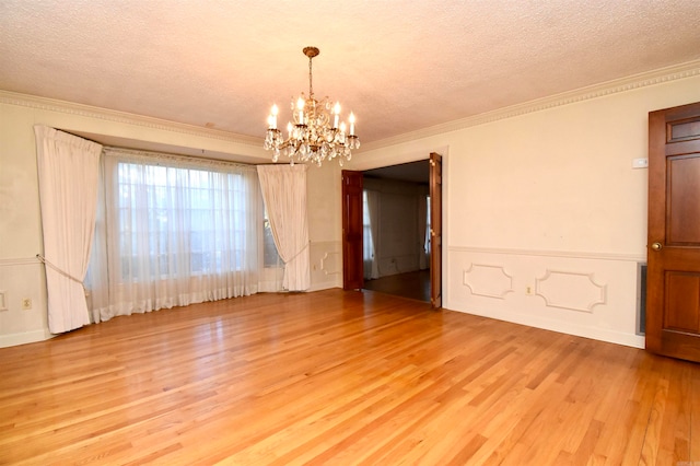 unfurnished room with a chandelier, a textured ceiling, light wood-type flooring, and crown molding