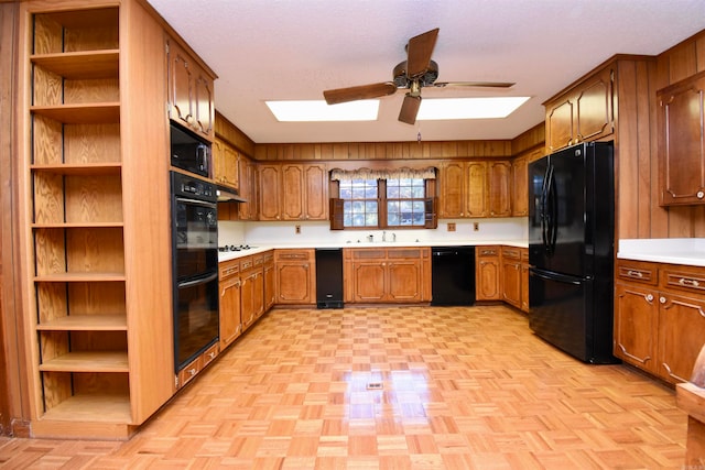 kitchen with black appliances, ceiling fan, light parquet floors, and sink