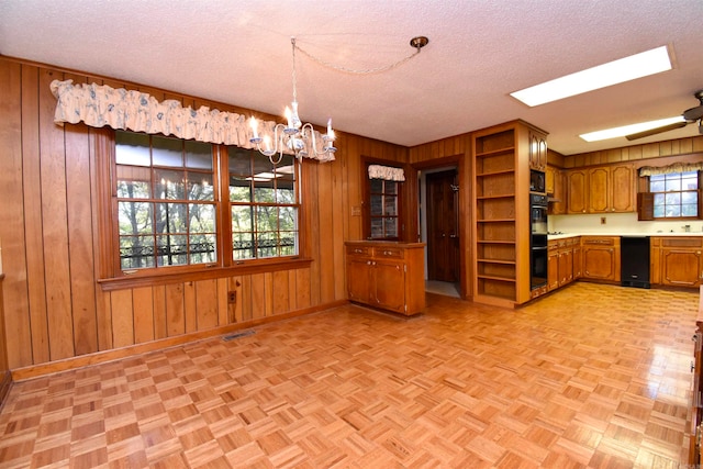 kitchen with a textured ceiling, wooden walls, and black double oven