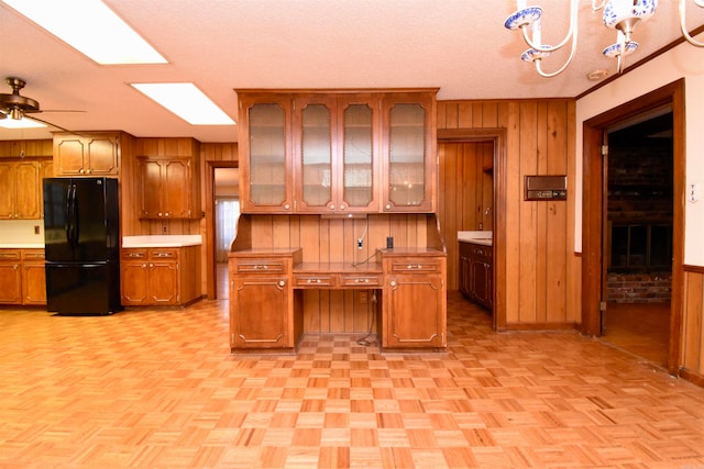 kitchen featuring wood walls, ceiling fan, a textured ceiling, and black fridge