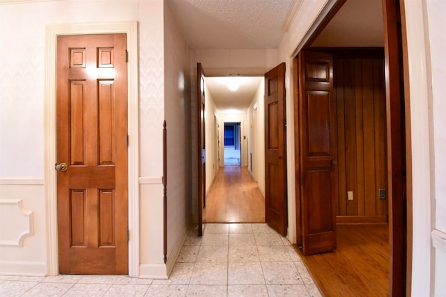 corridor with light hardwood / wood-style floors and a textured ceiling